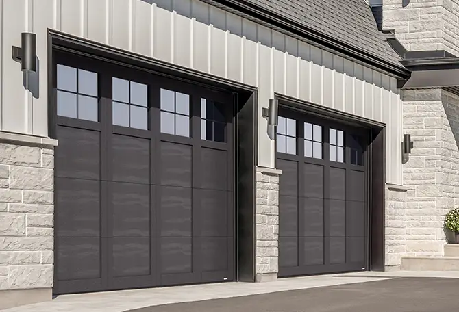 Maison de style transitionnel avec un mur en pierre gris chaud, portes de garage avec moulures en PVC, modèlePrinceton P-31.